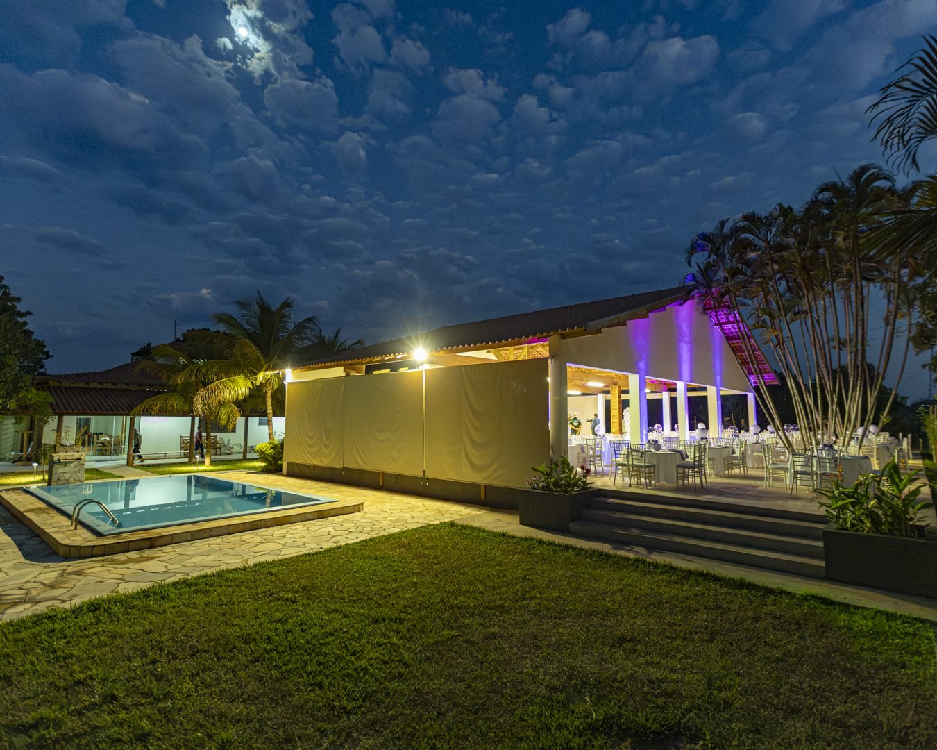 Salão e piscina iluminados durante aniversário ao luar