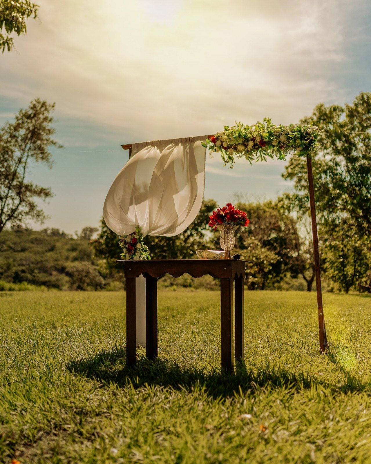 Altar com flores e tecido branco em área gramada