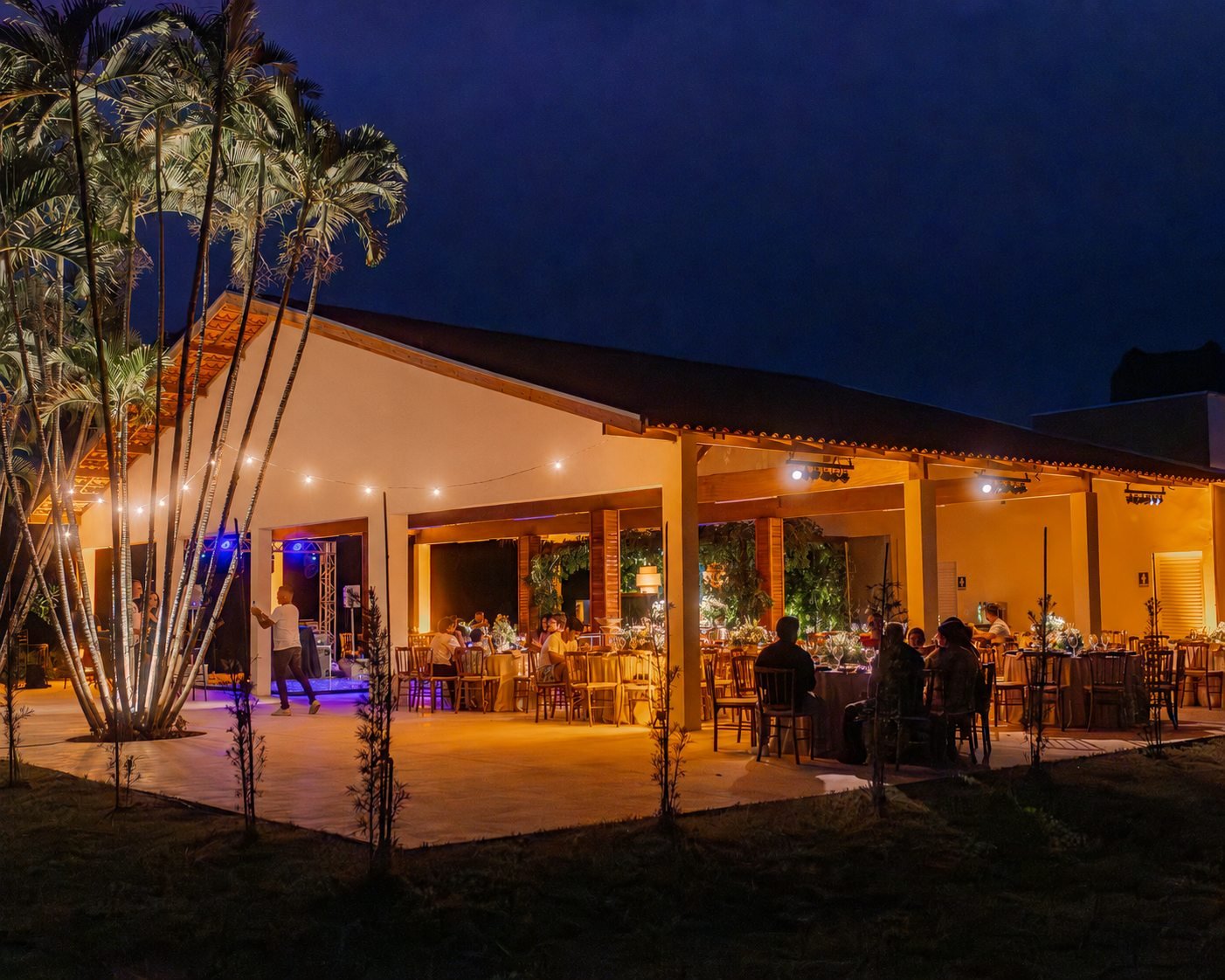 Evento noturno na fachada iluminada da chácara
